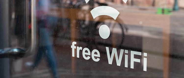 Symbol und Schrift für kostenloses WLAN auf der Fensterscheibe eines Geschäfts